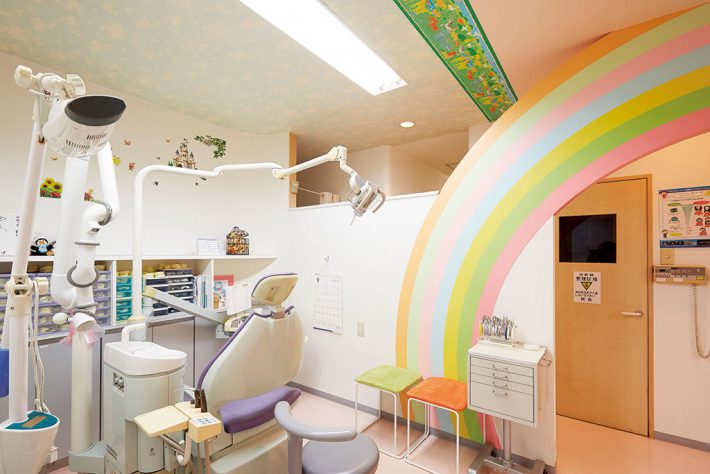 虹があしらわれた診察室の入口をくぐると、城戸先生をはじめスタッフの方々が、子供の患者さんを明るく出迎えます（クローヴァ歯科クリニック：都筑区北山田）